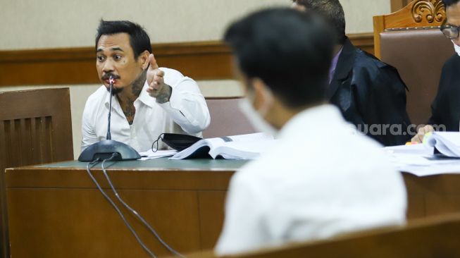 Musisi I Gede Ari Astina atau Jerinx SID mengajukan pertanyaan kepada Adam Deni yang hadir sebagai saksi saat sidang kasus pengancaman di Pengadilan Negeri Jakarta Pusat, Rabu (12/1/2022). [Kabarindong.com/Alfian Winanto]