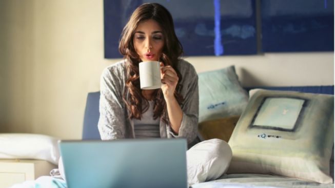 ilustrasi wanita diatas tempat tidur didepan laptop. (Pexels.com/faridahasanatul)