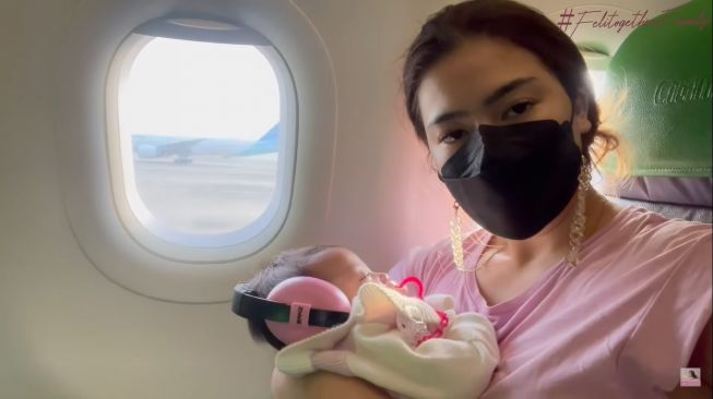 Felicya Angelista bersama Baby Bible di dalam pesawat menuju Bali. [Instagram]