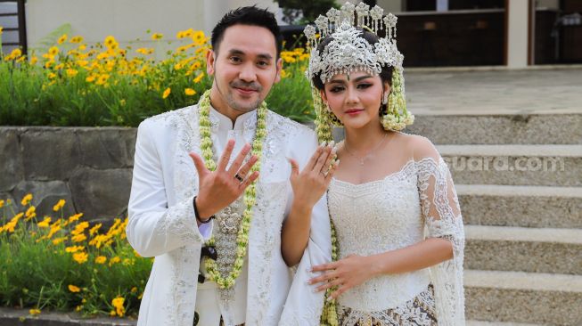 Pedangdut Jenita Janet dan suaminya, Danu Sofwan memamerkan cincin kawin di jari manis mereka usai melangsungkan pernikahan di Green Forest Resort, Bandung, Jawa Barat, Rabu (11/11). [Kabarindong.com/Alfian Winanto]