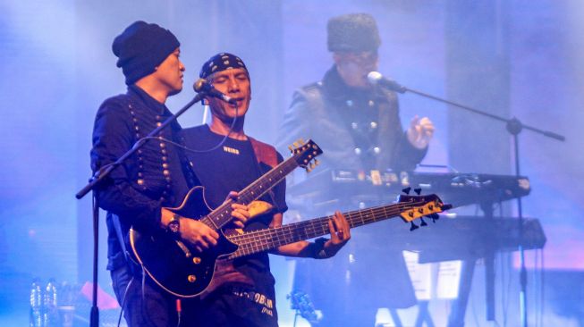 Personel band Dewa 19 Ahmad Dhani (kanan) dan Andra Ramadhan (kiri) Yuke Sampurna (tengah) beraksi saat konser di Lapangan Dakota Lanudal Juanda, Surabaya, Jawa Timur, Rabu (23/11/2022). ANTARA FOTO/Umarul Faruq